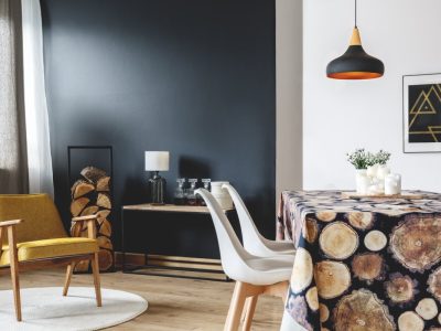 Dining room with yellow armchair, console table, logs holder and dining table with tablecloth decorated with logs of wood