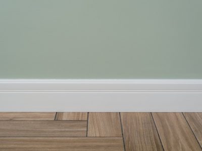 Interior concept. Light green matte wall, white baseboard and tiles immitating hardwood flooring