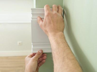 Closeup of gluing wooden white painted plank panel on wall, closeup, carpentry, woodwork, profession, people.